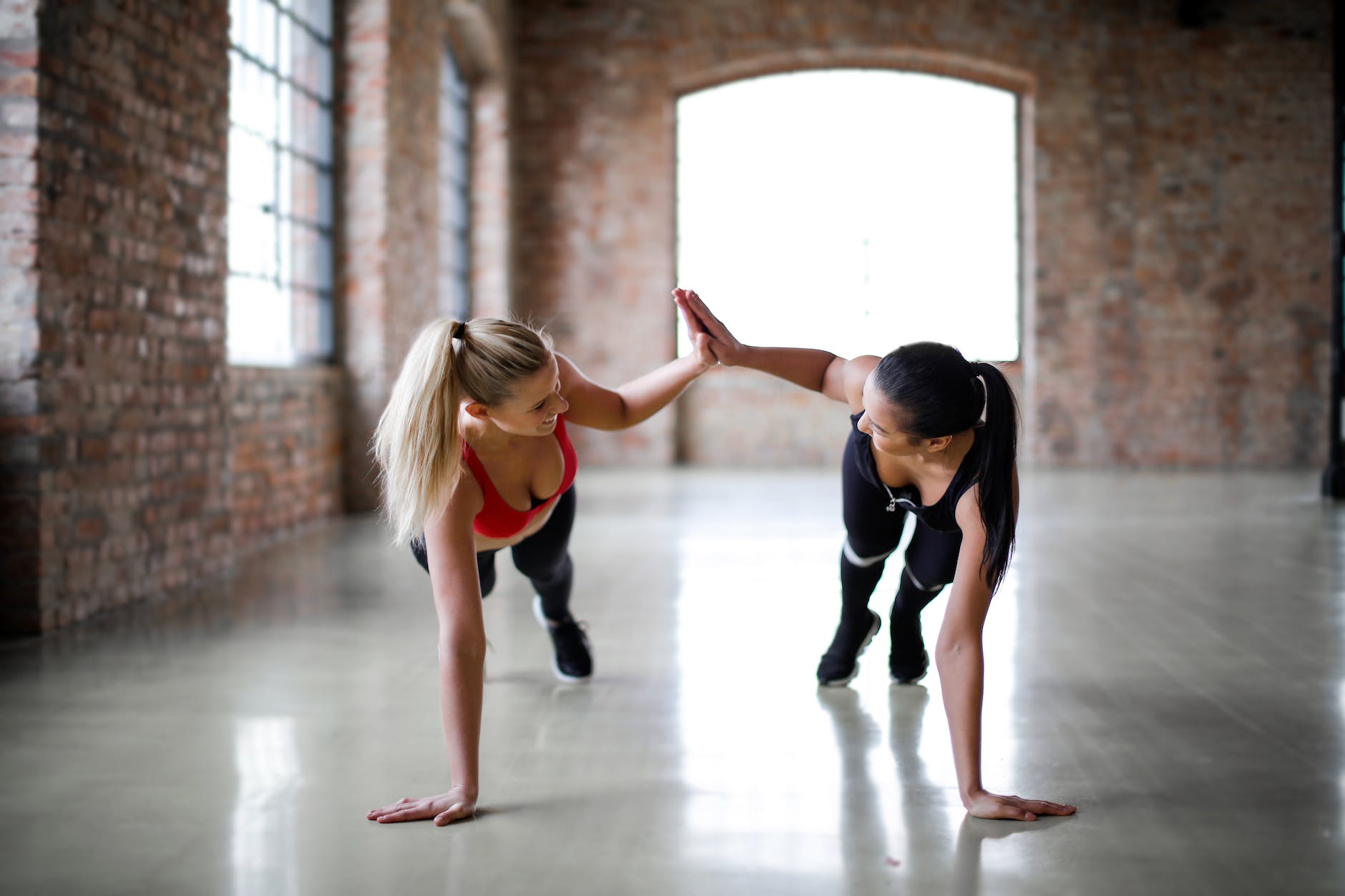 young slender female athletes giving high five to each other while training together in sports club. Celebrating effort before success