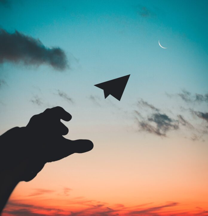 pexels-rakicevic-nenad-1262304 Being creative shown with a silhoutte of a hand throwing a paper plane.